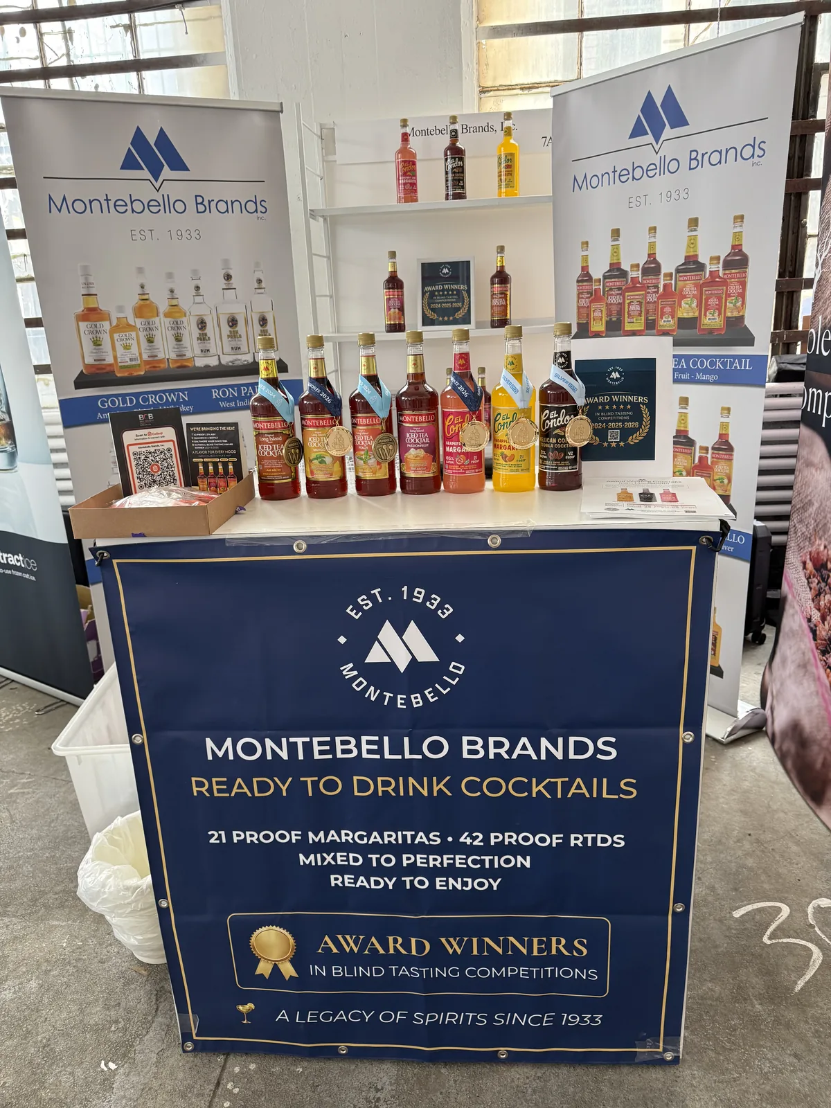 The Montebello Brands booth: ready-to-drink cocktails table with the award winners banner and a bottle wall behind it
